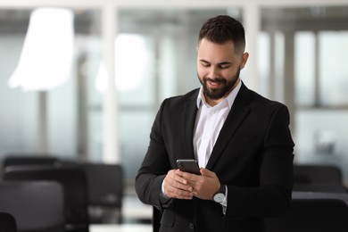 Smiling man with smartphone in office, space for text. Lawyer, businessman, accountant or manager