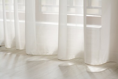 Photo of Curtain over sunlit wooden floor in morning