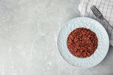 Photo of Flat lay composition with delicious cooked brown rice on grey table. Space for text