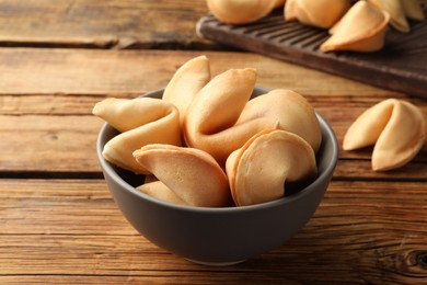 Tasty fortune cookies with predictions on wooden table, closeup