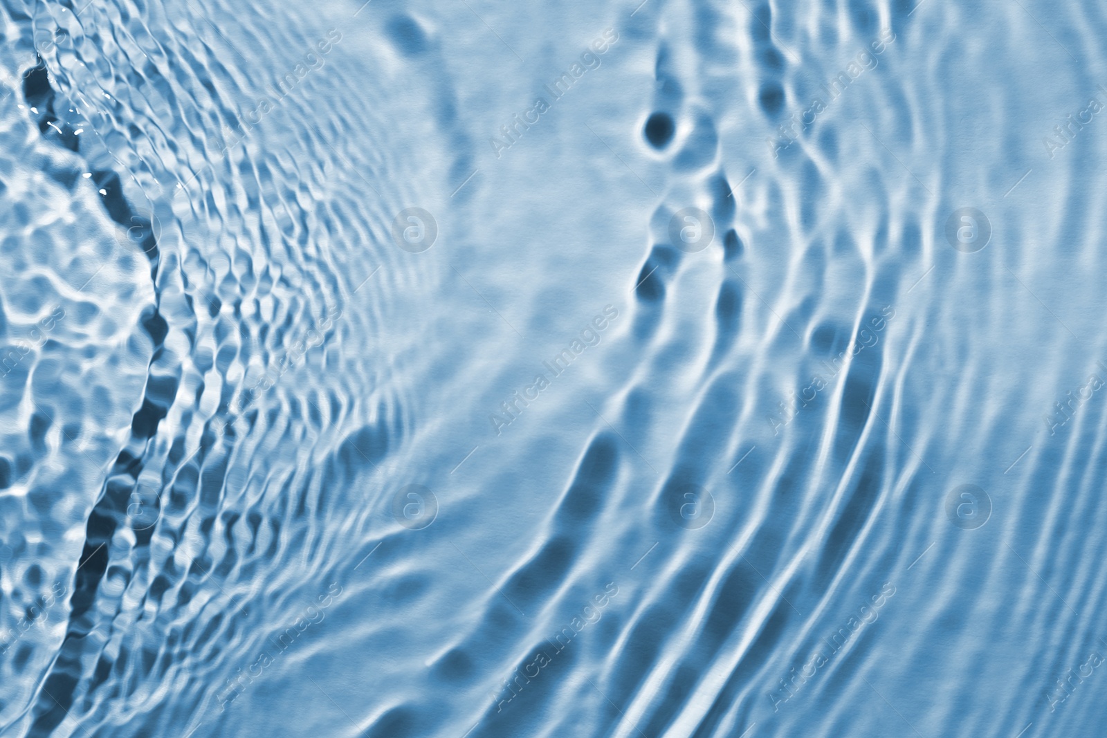 Image of Rippled surface of clear water on light blue background, closeup