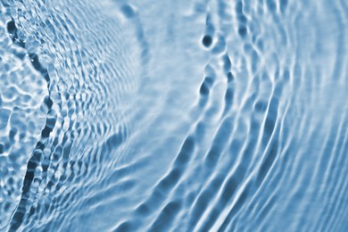 Rippled surface of clear water on light blue background, closeup
