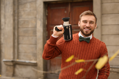 Young man with vintage video camera outdoors