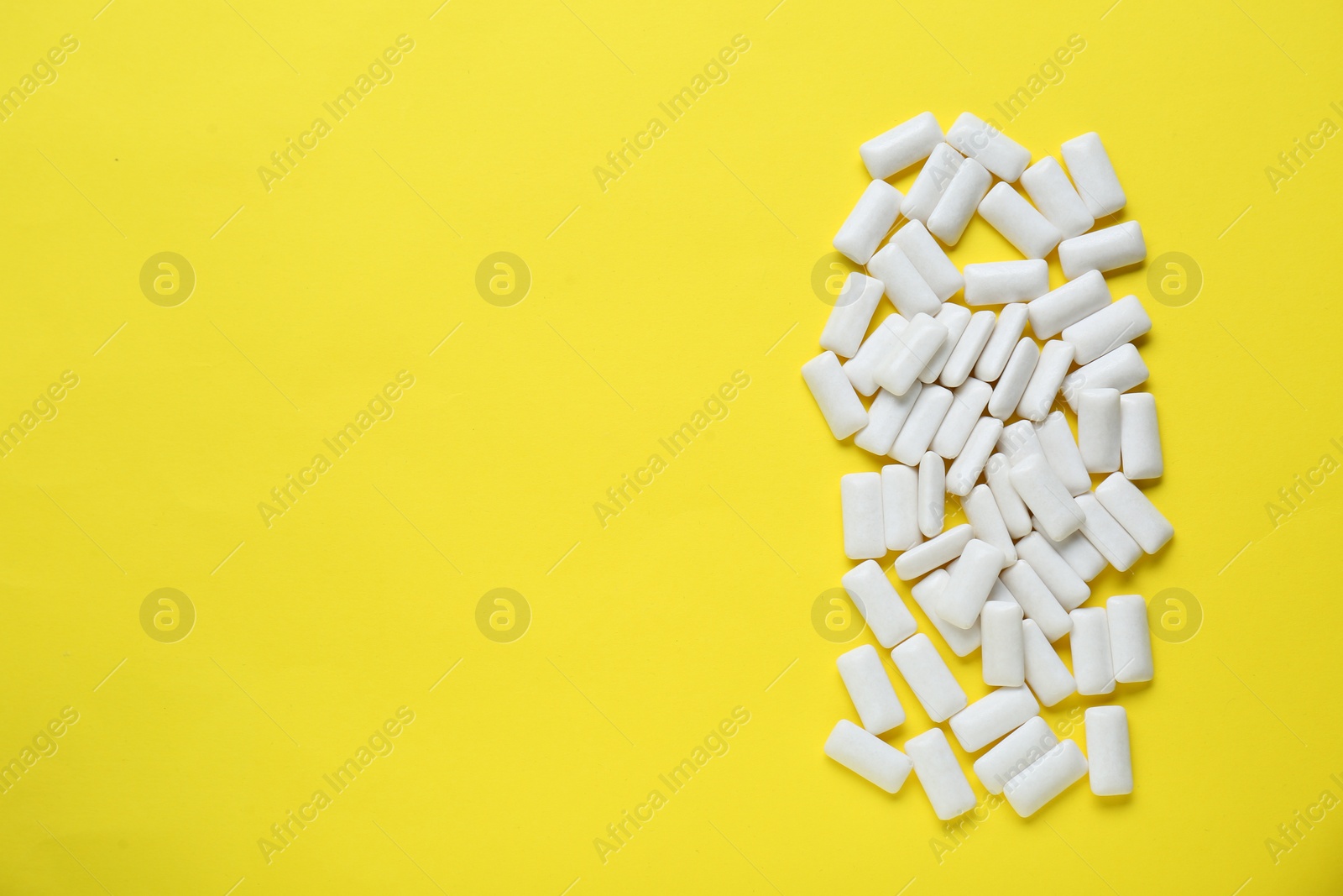 Photo of Tasty white chewing gums on yellow background, flat lay. Space for text