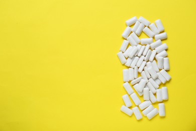 Photo of Tasty white chewing gums on yellow background, flat lay. Space for text