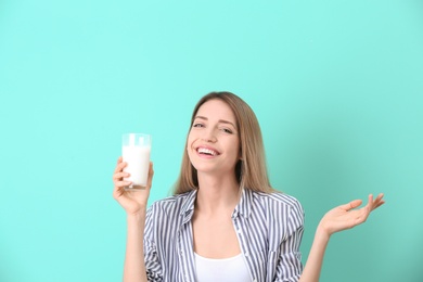 Photo of Beautiful young woman drinking milk on color background