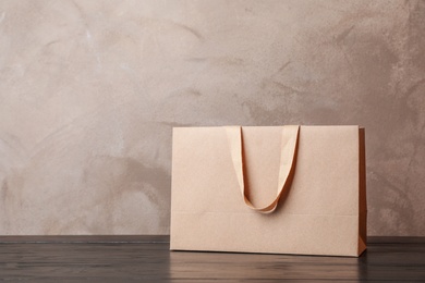 Photo of Paper shopping bag with handles on table against color wall. Mock up for design