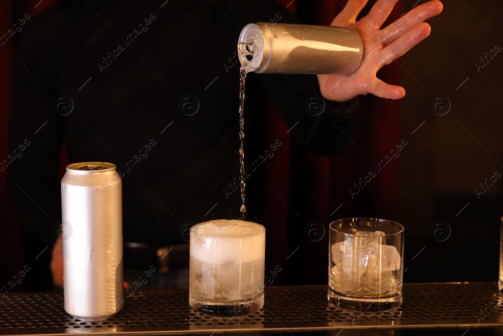 Photo of Bartender pouring energy drink into glass at counter in bar, closeup