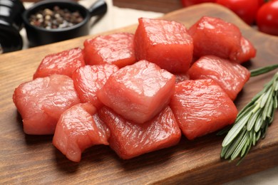 Cooking delicious goulash. Raw beef meat and rosemary on wooden board, closeup