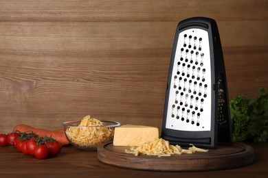 Photo of Grater, cheese and vegetables on wooden table. Space for text