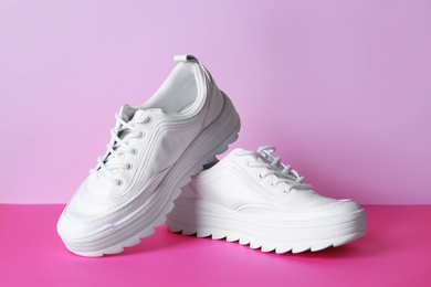 Photo of Pair of stylish sneakers on color background