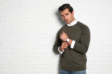 Portrait of handsome young man on white brick wall. Space for text