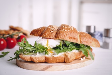 Delicious croissant with arugula and egg on white wooden table, closeup