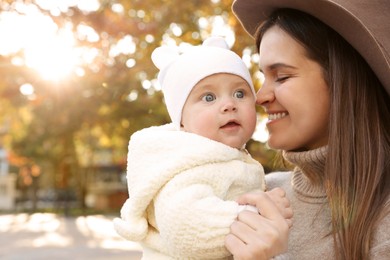 Photo of Happy mother with her baby daughter outdoors on autumn day, space for text