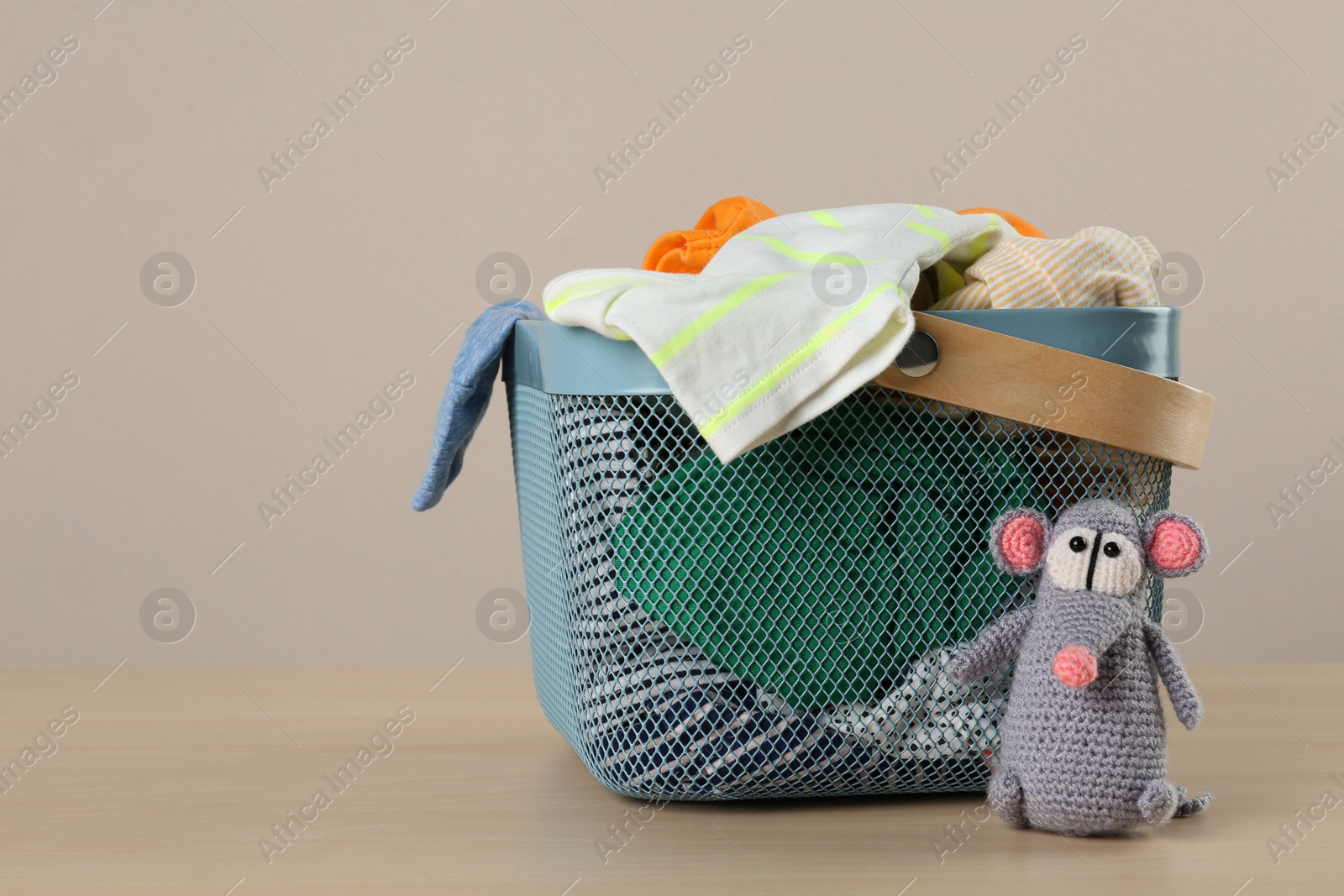 Photo of Laundry basket with different children's clothes and toy on wooden table. Space for text