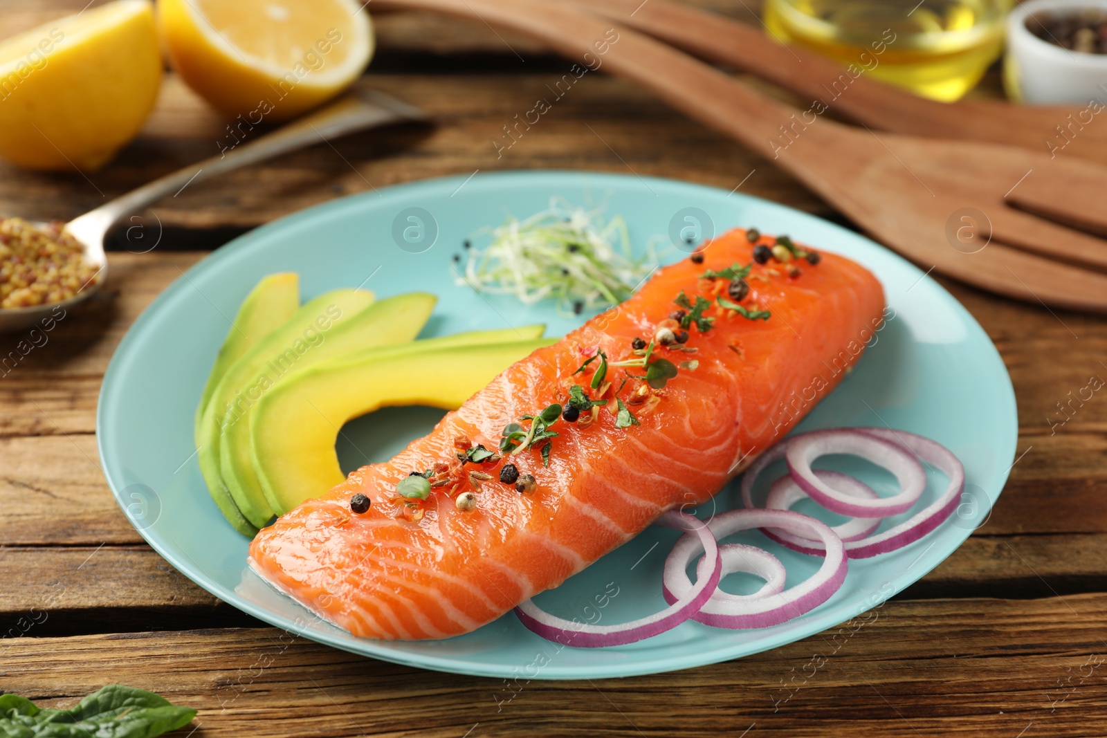 Photo of Delicious fresh salmon with spinach, avocado and onion served on wooden table