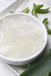 Aloe vera gel and slices of plant on white table, closeup