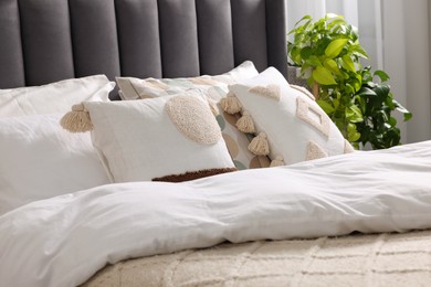Photo of Comfortable bed with pillows, duvet and beautiful houseplants indoors. Stylish interior