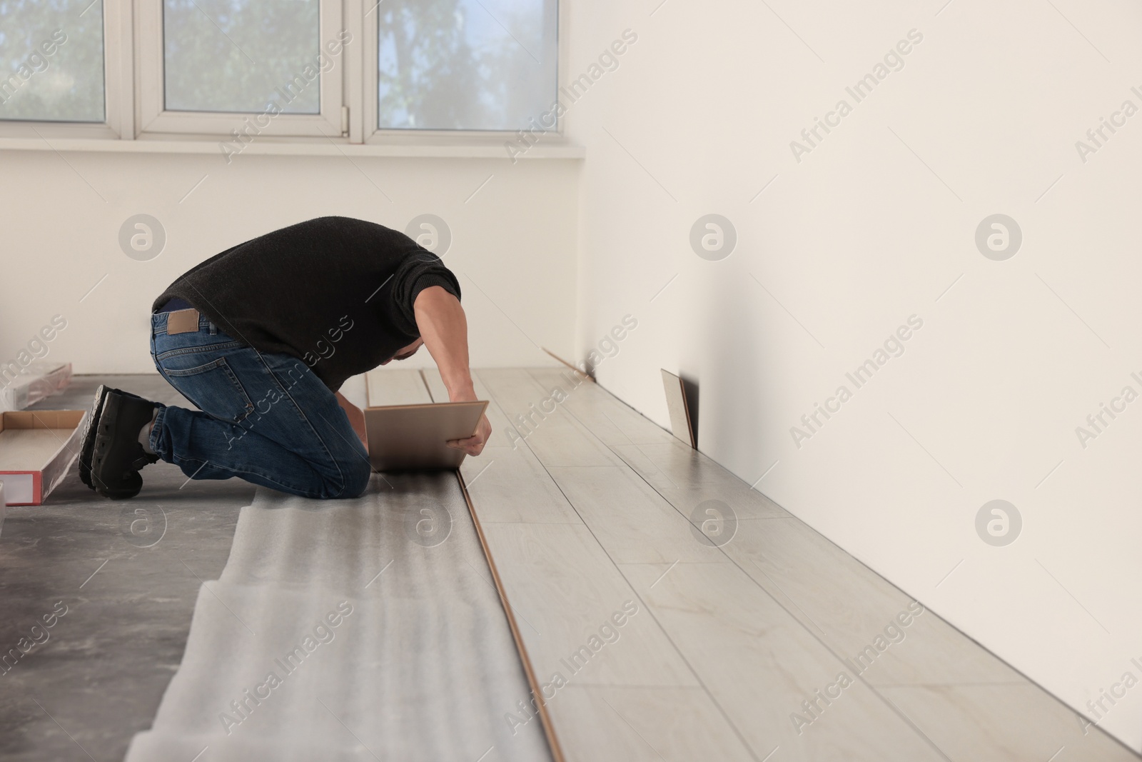 Photo of Professional worker installing new laminate flooring. Space for text