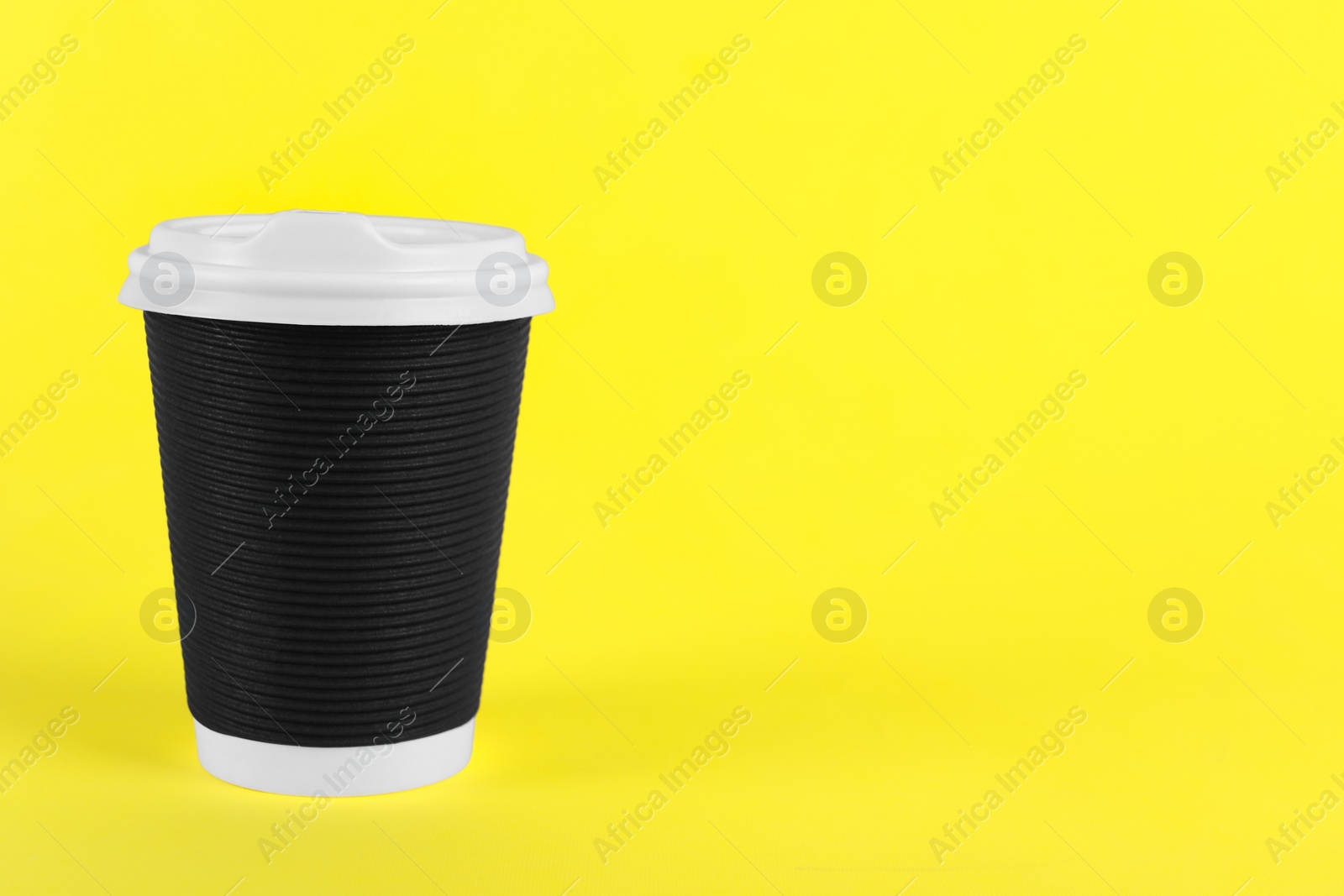 Photo of Black paper cup with plastic lid on yellow background, space for text. Coffee to go