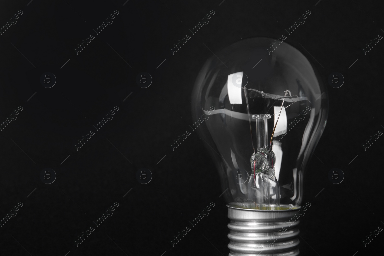 Photo of New modern lamp bulb on black background, space for text