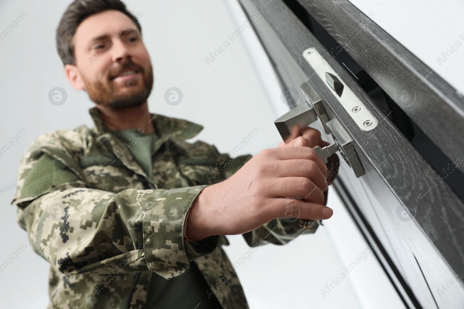 Photo of Soldier unlocking door with key indoors, low angle view and selective focus. Military service
