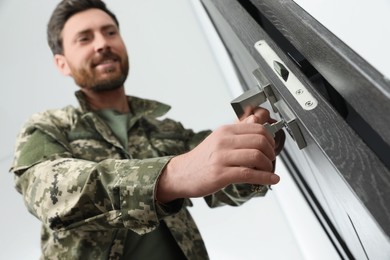 Photo of Soldier unlocking door with key indoors, low angle view and selective focus. Military service