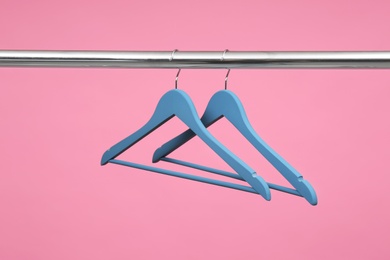 Photo of Empty clothes hangers on metal rail against color background