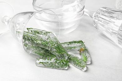 Overturned glass of ice cubes with cedar branches on light table