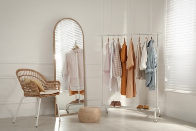 Photo of Modern dressing room interior with stylish clothes, shoes and large mirror