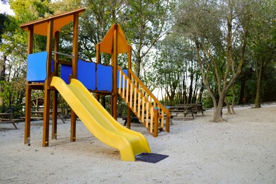 Photo of Empty playground with beautiful slide, benches and trees in park. Space for text