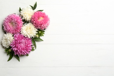 Photo of Beautiful asters and space for text on white wooden background, flat lay. Autumn flowers