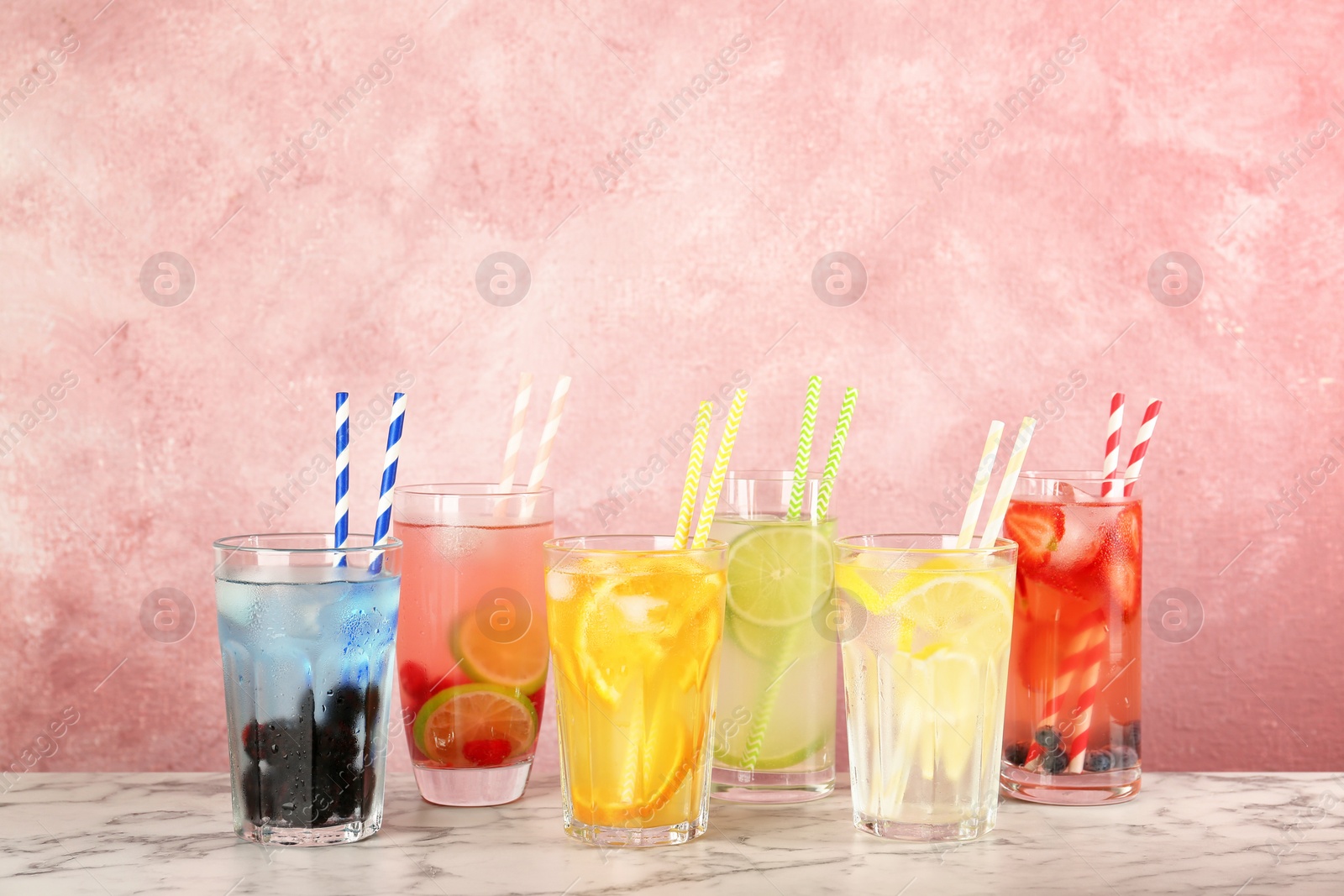 Photo of Glasses with lemonades on table against color background