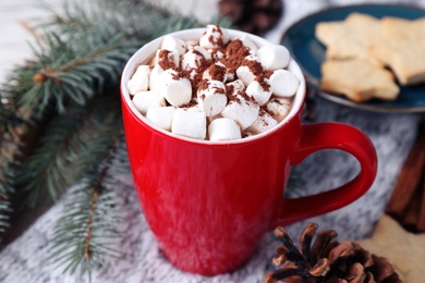 Photo of Cup of tasty cocoa with marshmallows on knitted cloth, closeup