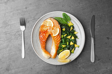 Photo of Tasty salmon with spinach served on grey table, flat lay