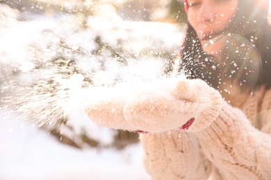 Young woman blowing snow outdoors, closeup. Winter vacation