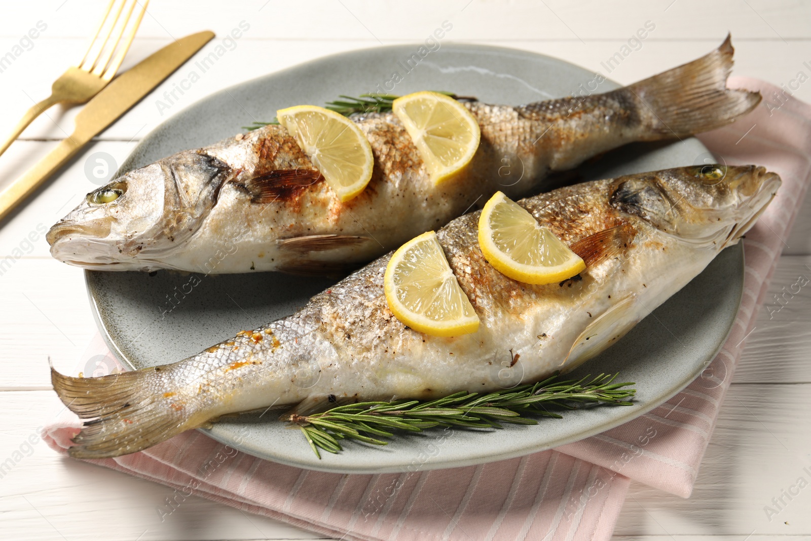 Photo of Delicious baked fish served on white wooden table