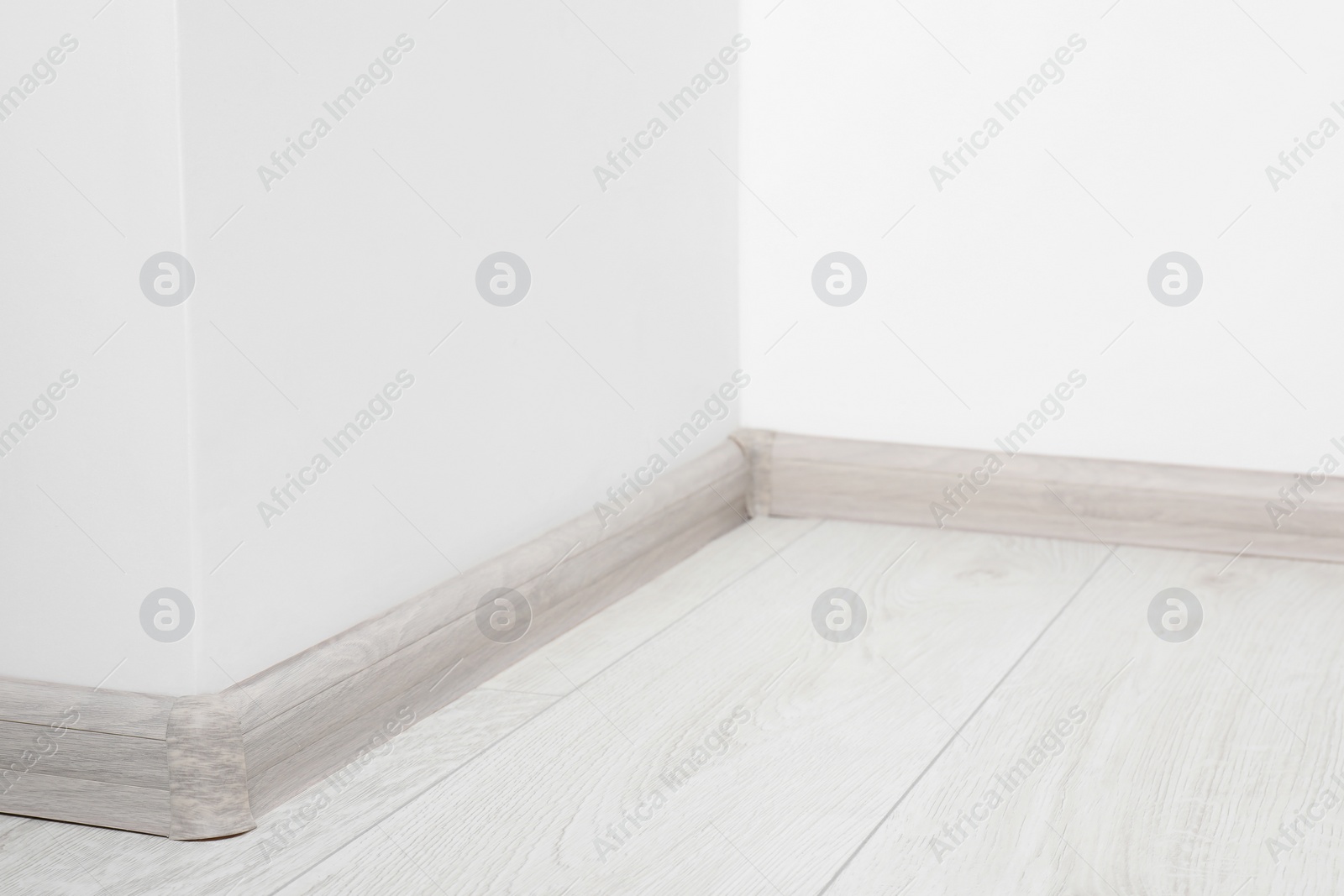 Photo of Wooden plinth with connectors on laminated floor near white wall indoors