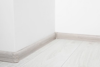 Photo of Wooden plinth with connectors on laminated floor near white wall indoors