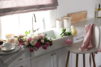 Photo of Bunch of beautiful peonies in kitchen sink