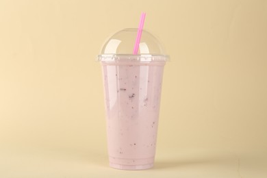 Photo of Plastic cup of tasty smoothie on beige background