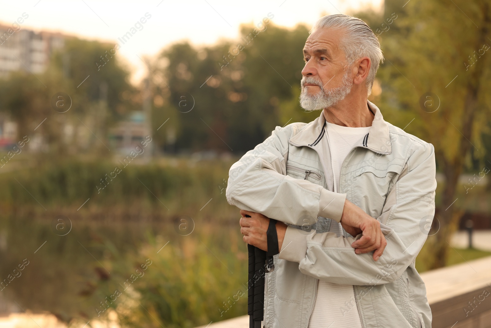 Photo of Senior man with Nordic walking poles outdoors, space for text