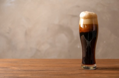 Photo of Glass of cold dark beer on wooden table