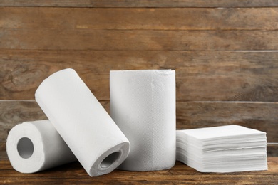 Photo of Clean napkins and rolls of paper towels on wooden table