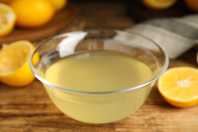 Photo of Freshly squeezed lemon juice in glass bowl on wooden table