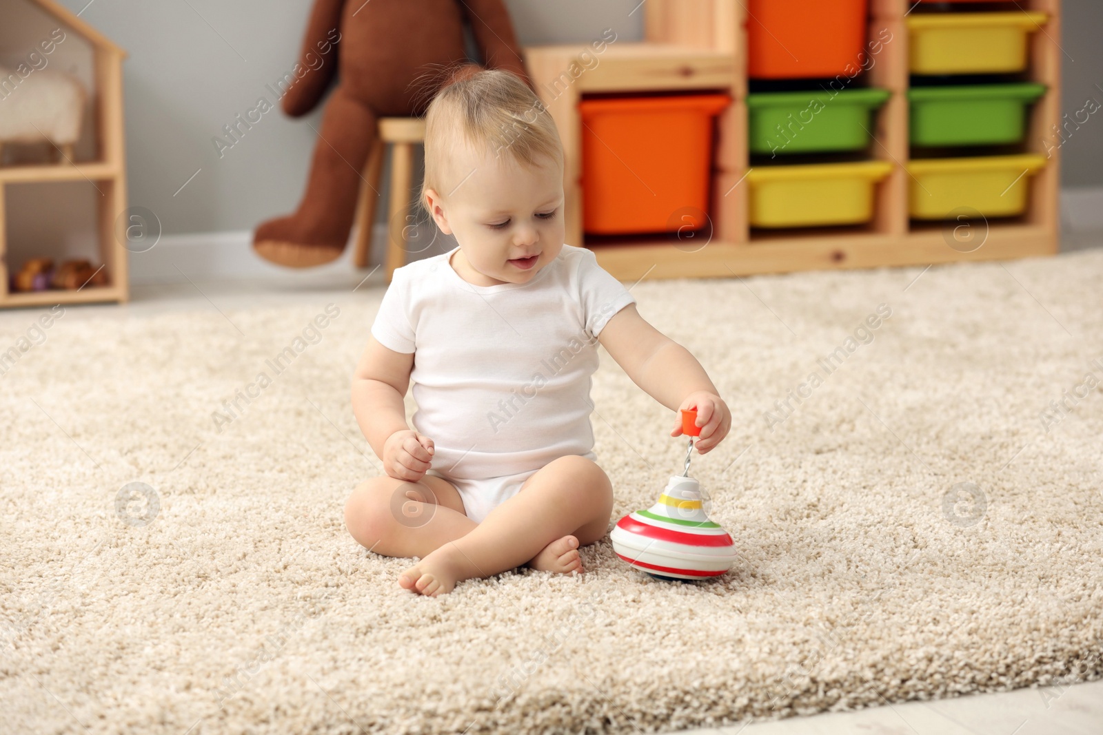 Photo of Children toys. Cute little boy playing with spinning top on rug at home