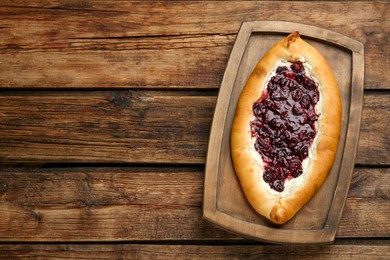 Delicious sweet cottage cheese pastry with cherry jam on wooden table, top view. Space for text