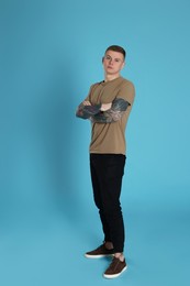 Photo of Young man with tattoos on light blue background