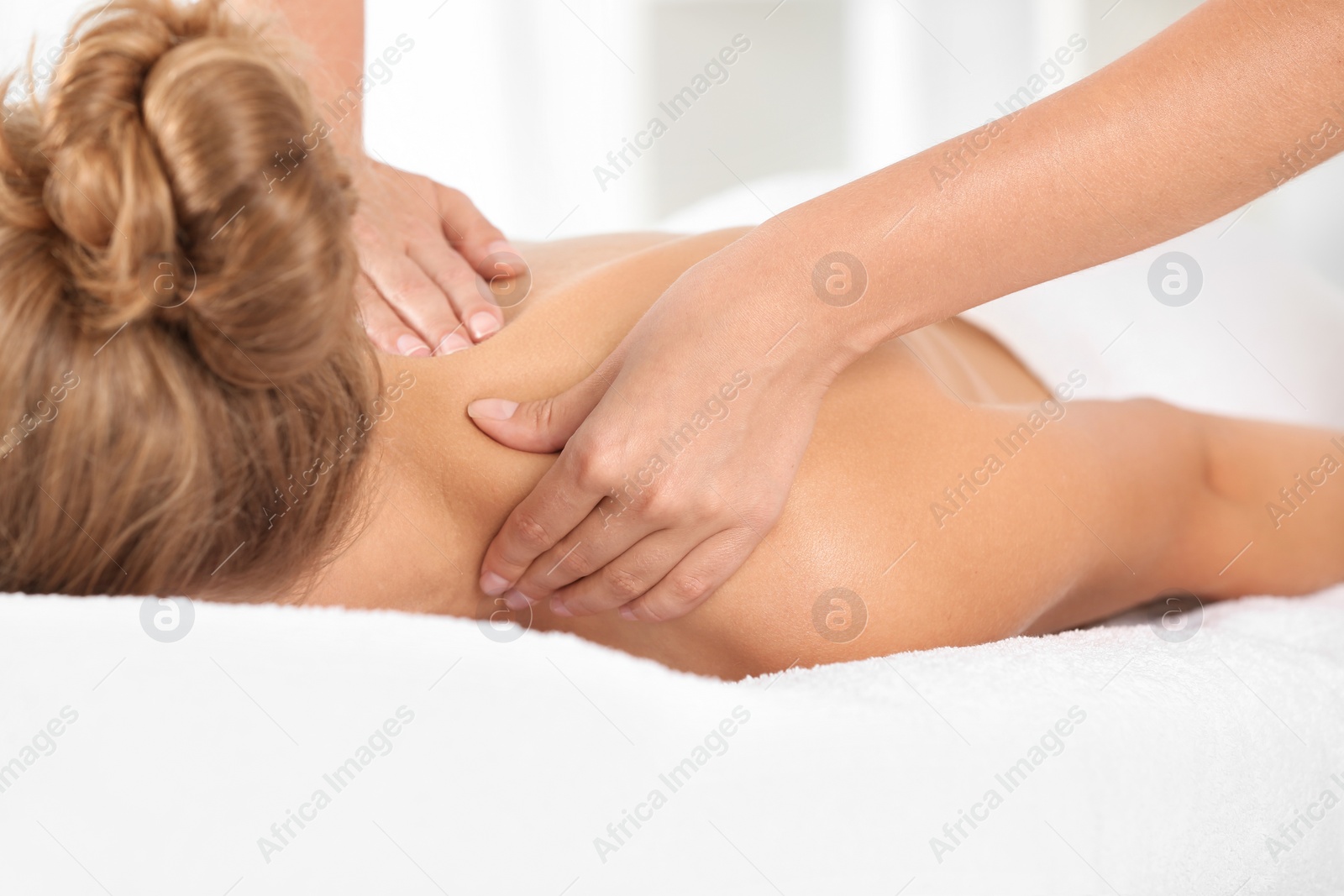 Photo of Relaxed woman receiving shoulders massage in wellness center