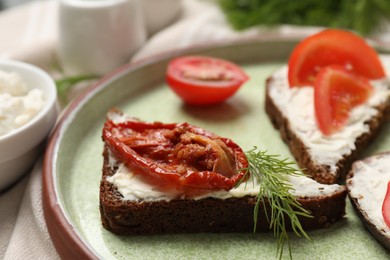 Delicious bruschetta with ricotta cheese, sun dried tomato and dill on table, closeup